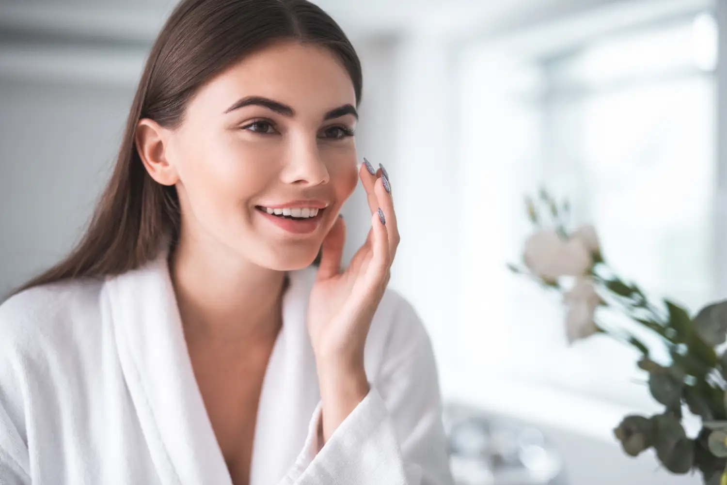 woman smiling and applying skincare product to face