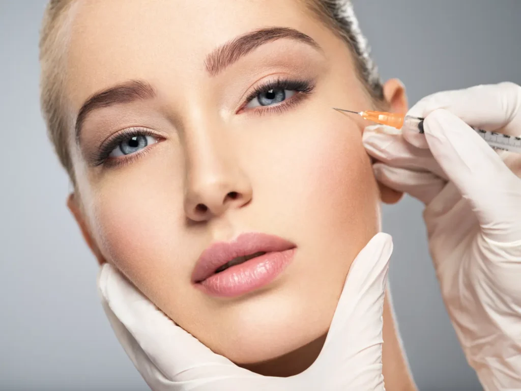 Close-up of a practitioner preparing an injectable treatment near the outer eye area.